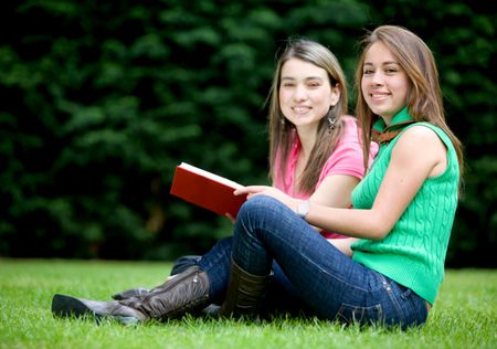 Casual female students reading a book outdoors