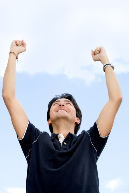 Successful and confident man with arms up outdoors