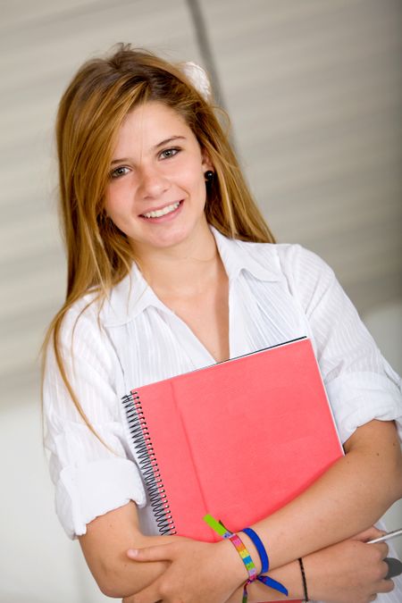 Beautiful female student holding a notebook and smiling