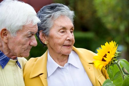 Beautiful couple of elder people looking a sunflower