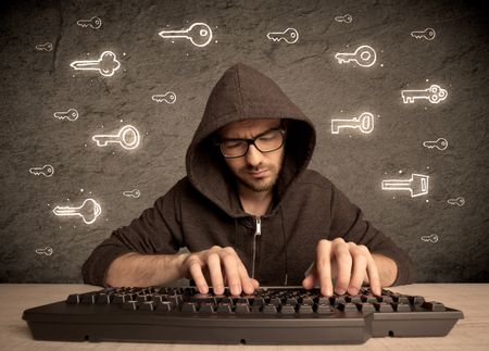 A young internet geek working online, hacking login passwords of social media users concept with glowing drawn keys on the wall