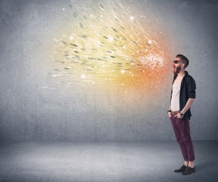 A young hipster guy with beard and sunglasses shouting in front of urban wall with vomit like colorful paint splatter on wall concept