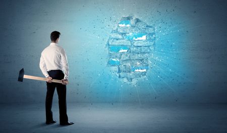 Business man hitting grungy brick wall with huge hammer