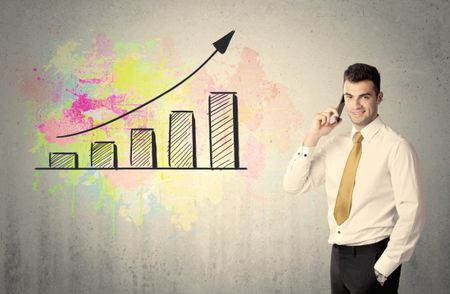 elegant-businessman-standing-front-grey-wall-457368574 An elegant businessman standing in front of a grey wall with colorful growing chart drawing concept