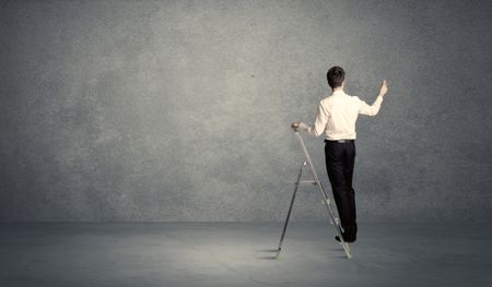 A man standing on ladder drawing with chalk in his hand on clear wall pattern background