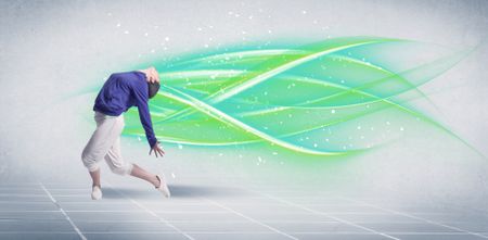 A good looking fresh street dancer dancing in front of grey background with white and bright, colorful green lines concept