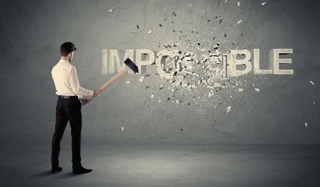 Business man hitting impossible sign with hammer on grungy wall