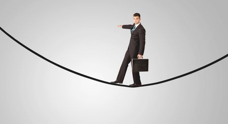 A confident smiling salesman balancing on black wire in clear grey empty space concept