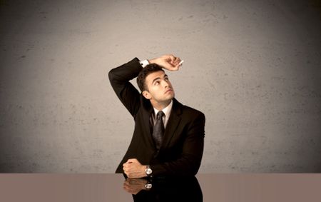 A happy businessman sitting at desk in front of clear grey empty background and drawing around himself with a white chalk concept
