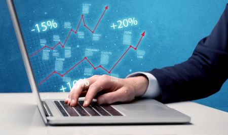 An elegant businessman working on graph statistics calculation using a laptop with clear blue background concept