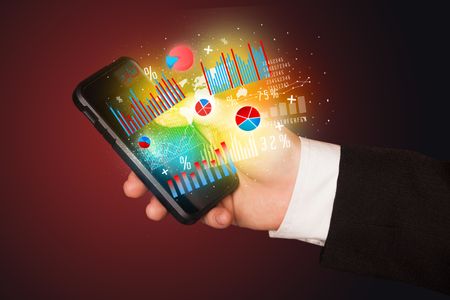 Business man holding smartphone with chart symbols concept