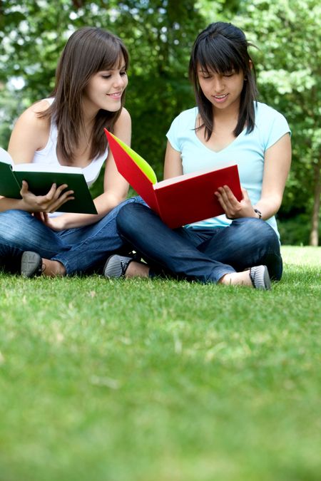 Female students reading a book at the park
