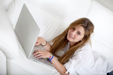 Girl lying on a sofa with a laptop