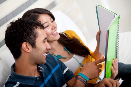 Happy couple with a notebook studying at home