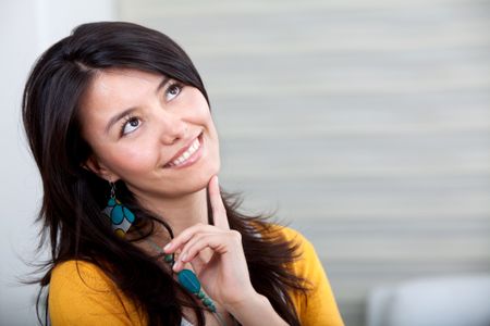 Beautiful thoughtful woman looking up and smiling - indoors