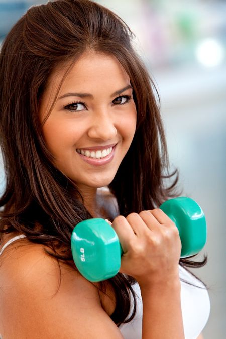 Bautiful woman at the gym lifiting free weights