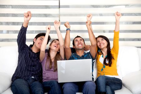 Excited group of friends at home with a laptop