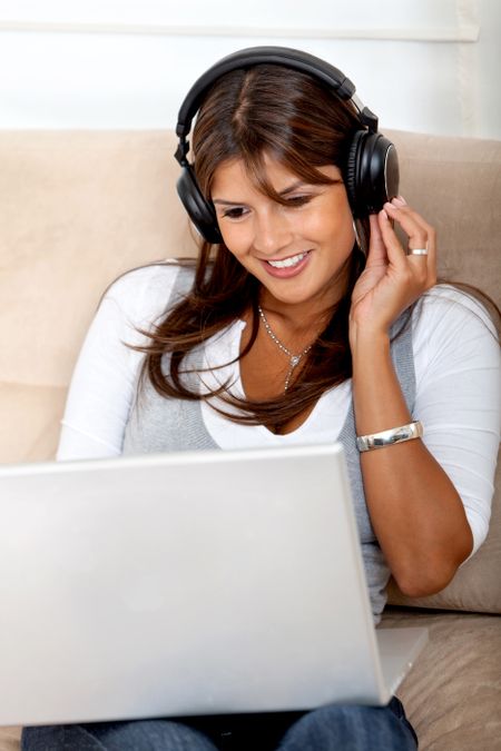 Woman wearing headphones downloading music from her computer