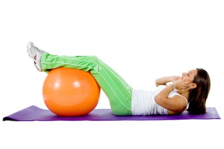 Woman doing abdominals with a pilates ball isolated on white