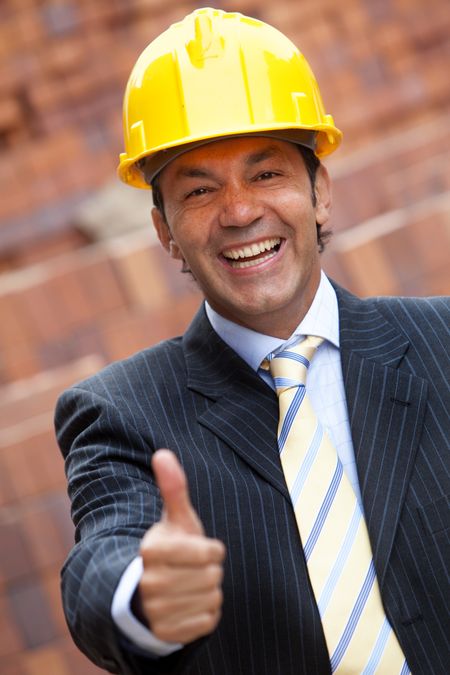 Male engineer with thumbs up at a construction site