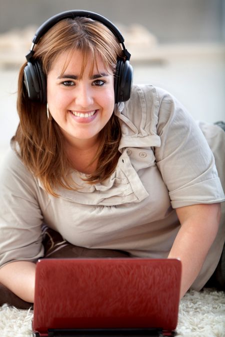 Woman wearing headphones downloading music from her computer