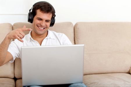 Man wearing earphones downloading music from her computer