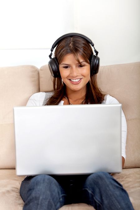 Woman wearing headphones downloading music from her computer