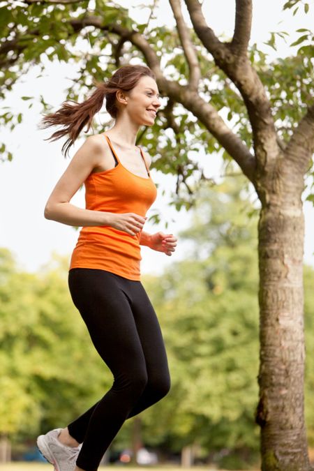 Beautiful happy woman running at the park