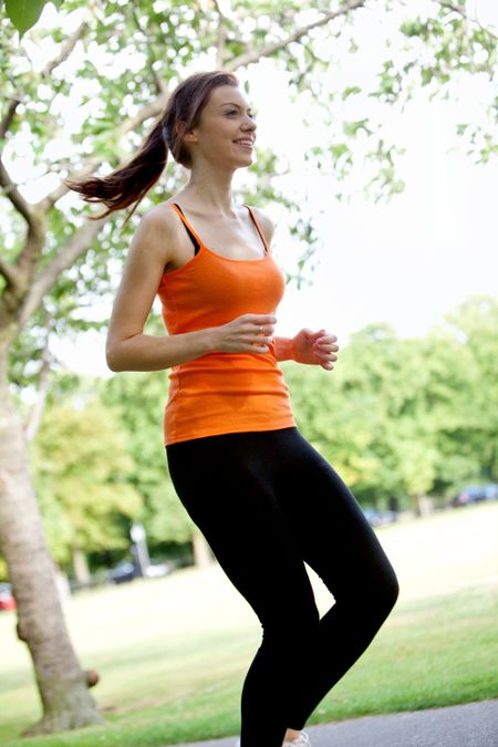 Beautiful happy woman running at the park