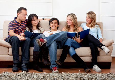Happy group of students sitting on a couch studying indoors