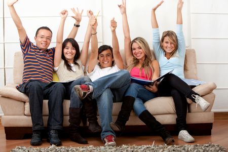 Group of exciting students with arms up indoors