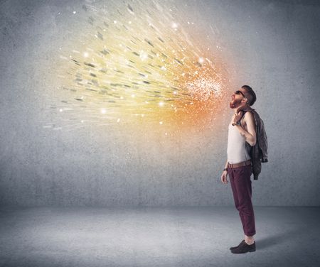 A young hipster guy with beard and sunglasses shouting in front of urban wall with vomit like colorful paint splatter on wall concept