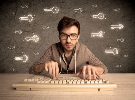 A young internet geek working online, hacking login passwords of social media users concept with glowing drawn keys on the wall