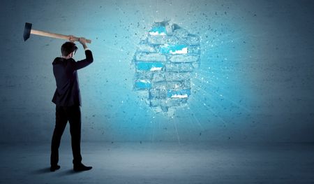 Business man hitting grungy brick wall with huge hammer