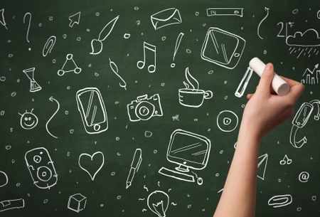 A person drawing media and communication icons on school blackboard with chalk