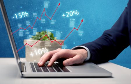 An elegant businessman working on graph statistics calculation using a laptop with clear blue background concept