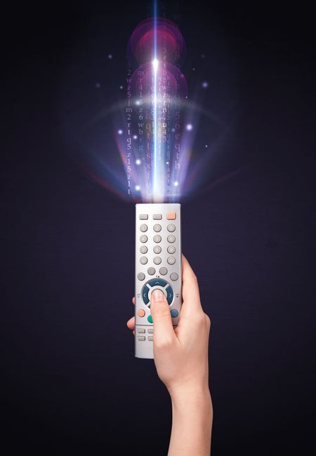 Hand holding a remote control, shining numbers and letters coming out of it