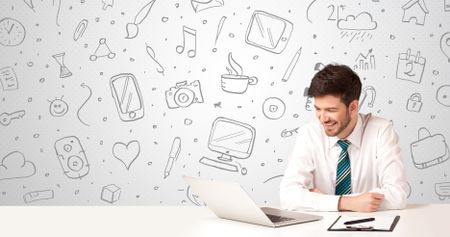 Businessman sitting at table with hand drawn media icons and symbols 