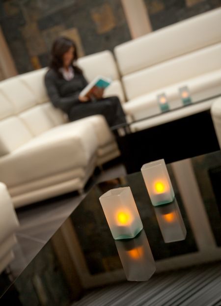 Woman reading indoors with some candles on the table
