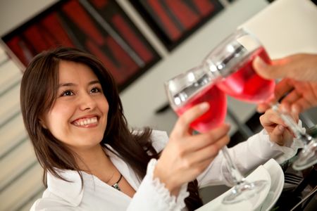 Beautiful woman toasting at a restaurant looking happy