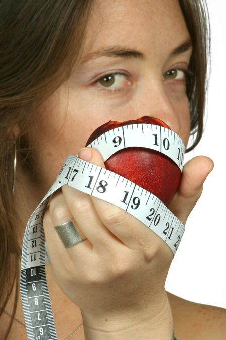 woman showing a fruit with measuring tape around it representing health and fitness