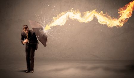 Business man defending himself from a fire arrow with an umbrella on grungy background