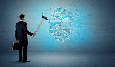 Business man hitting grungy brick wall with huge hammer