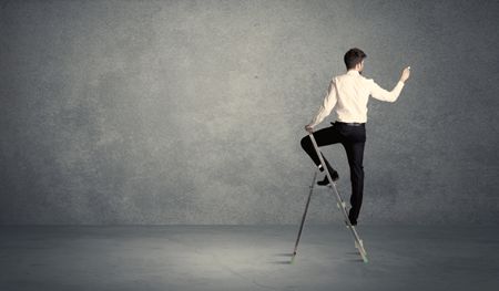 A man standing on ladder drawing with chalk in his hand on clear wall pattern background