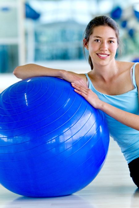 Gym woman with a pilates ball sitting on the floor