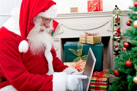 Santa Claus at home with a laptop pointing at the screen