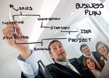 man drawing a business plan and showing it to a group