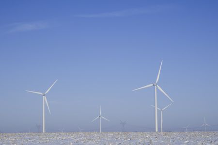 Wind turbines and distant power pylons stand above wintry corn field in northern Illinois