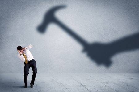 Business person afraid of a shadow hand holding hammer concept on background