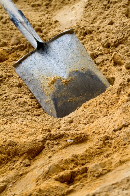 Construction shovel hammered in yellow sand - building materials